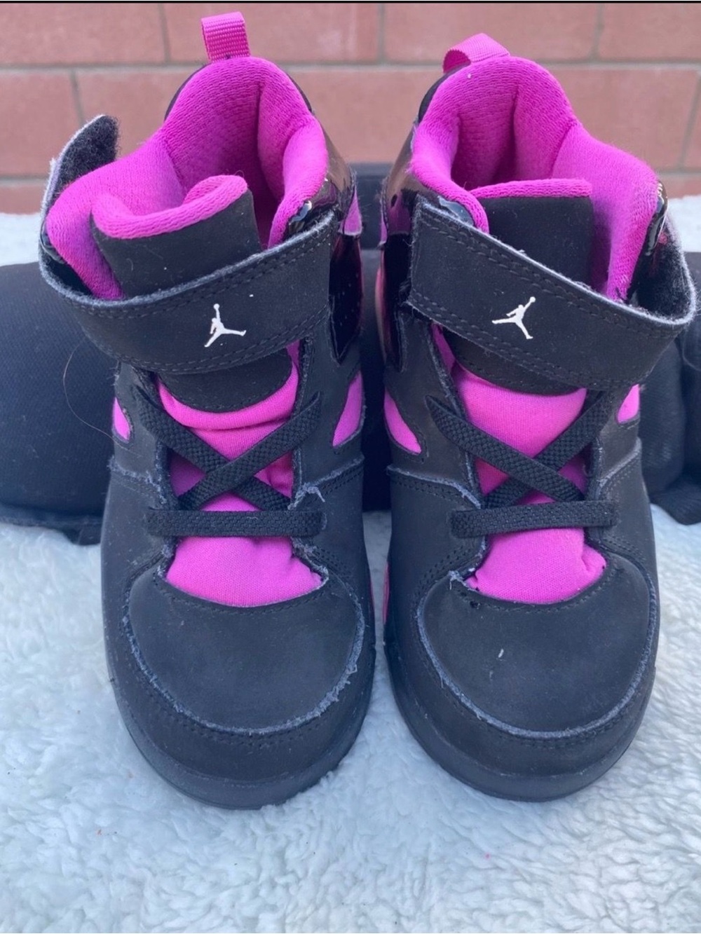 Jordan kids high-top sneakers in black with bright pink/purple accents.